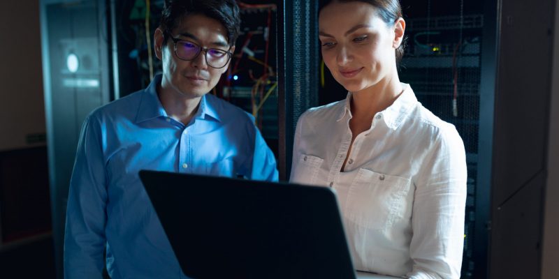 Digitale Zusammenarbeit im öffentlichen Sektor Zwei IT-Fachkräfte arbeiten gemeinsam an einem Laptop – digitale Zusammenarbeit und moderne Technologien im öffentlichen Sektor.