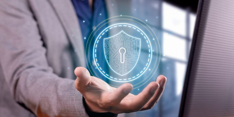 Cybersicherheit & Datenschutzlösungen Symbolische Darstellung von Cybersicherheit – Geschäftsperson hält digitales Sicherheitssymbol zum Schutz sensibler Daten.